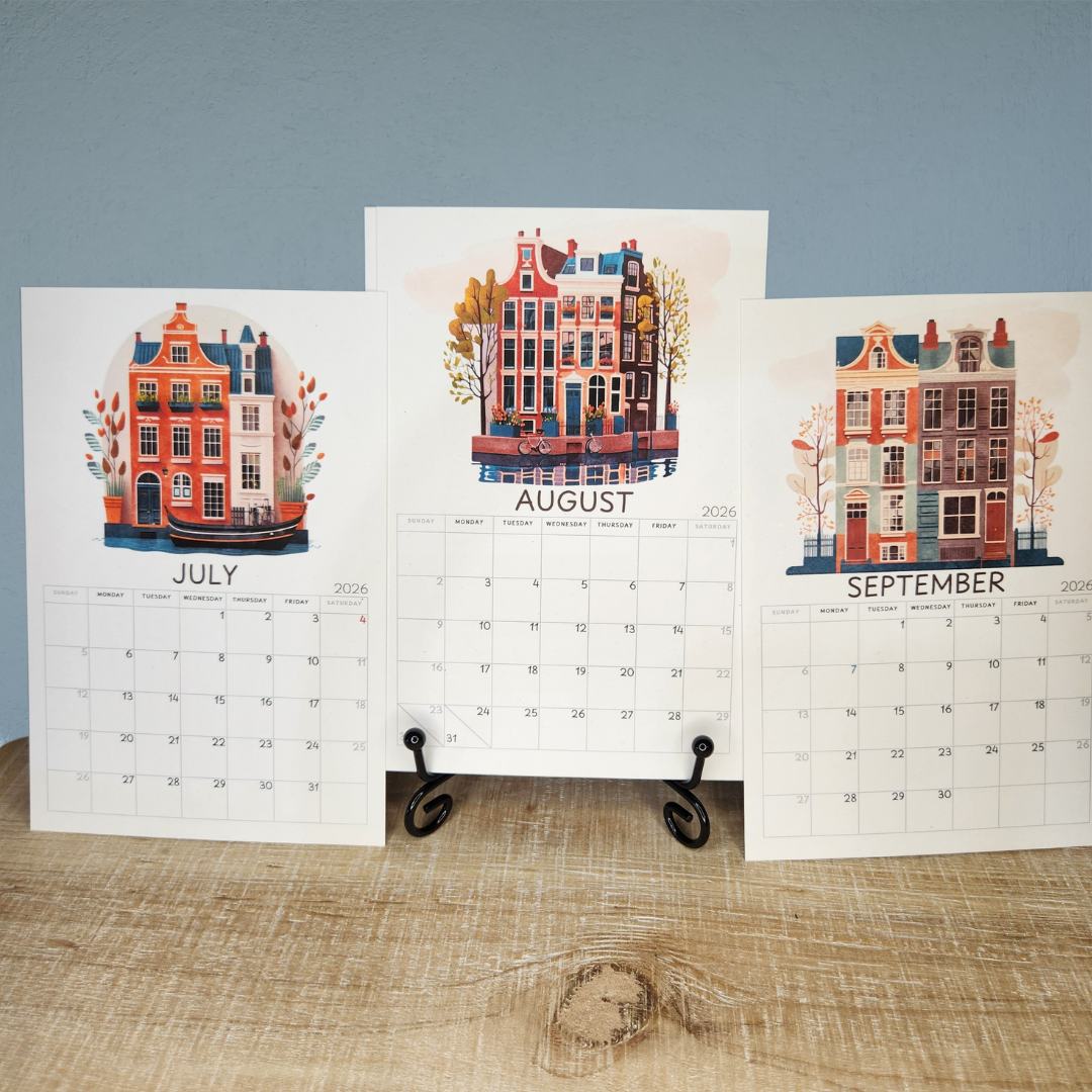 Calendar with illustrations of buildings for July, August, and September on a wooden surface.