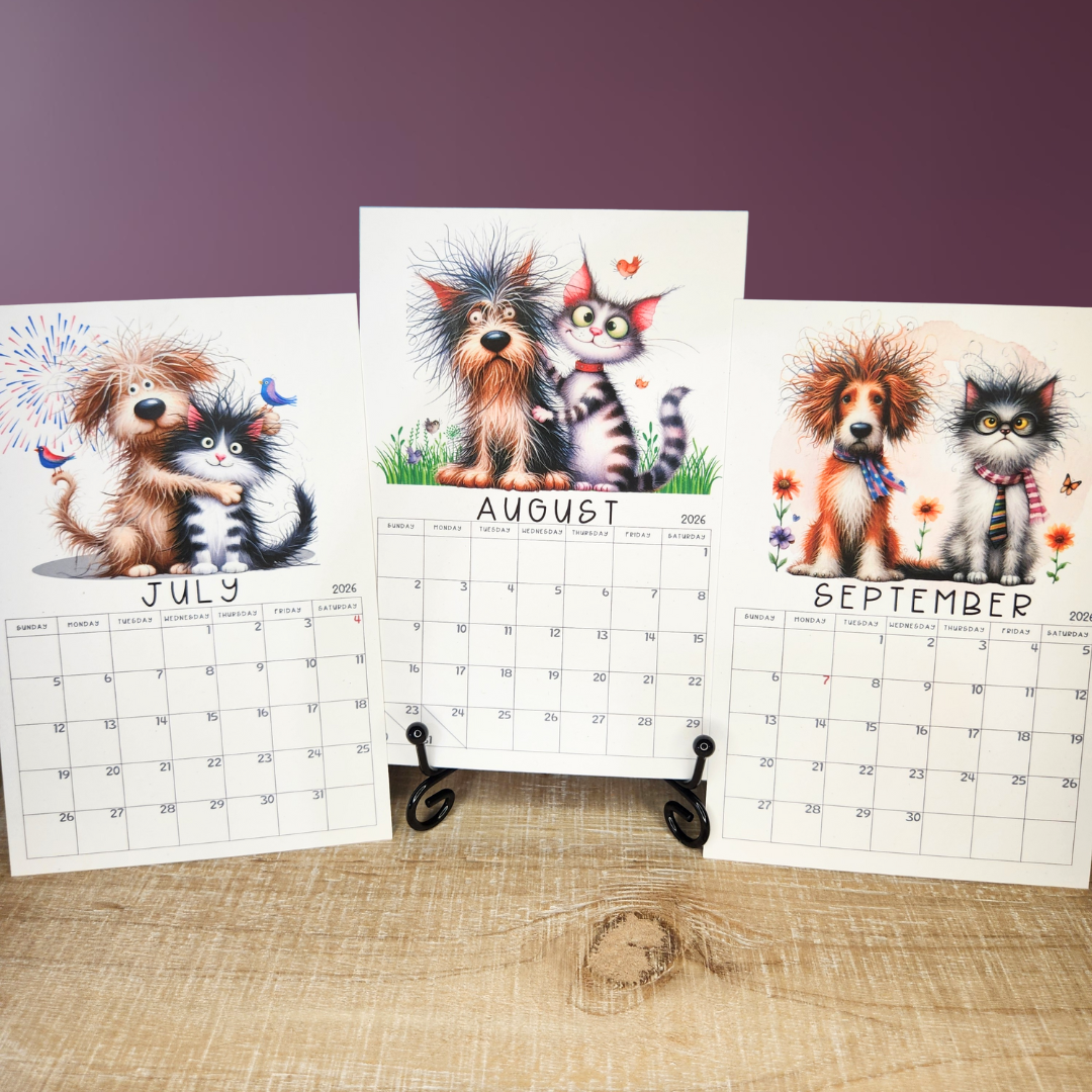 Three calendar pages showing dogs and cats for July, August, and September on a wooden surface with a purple wall background.