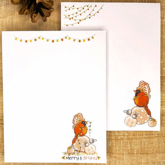 Two greeting cards with winter-themed illustrations of a robin and snowman on a textured surface.