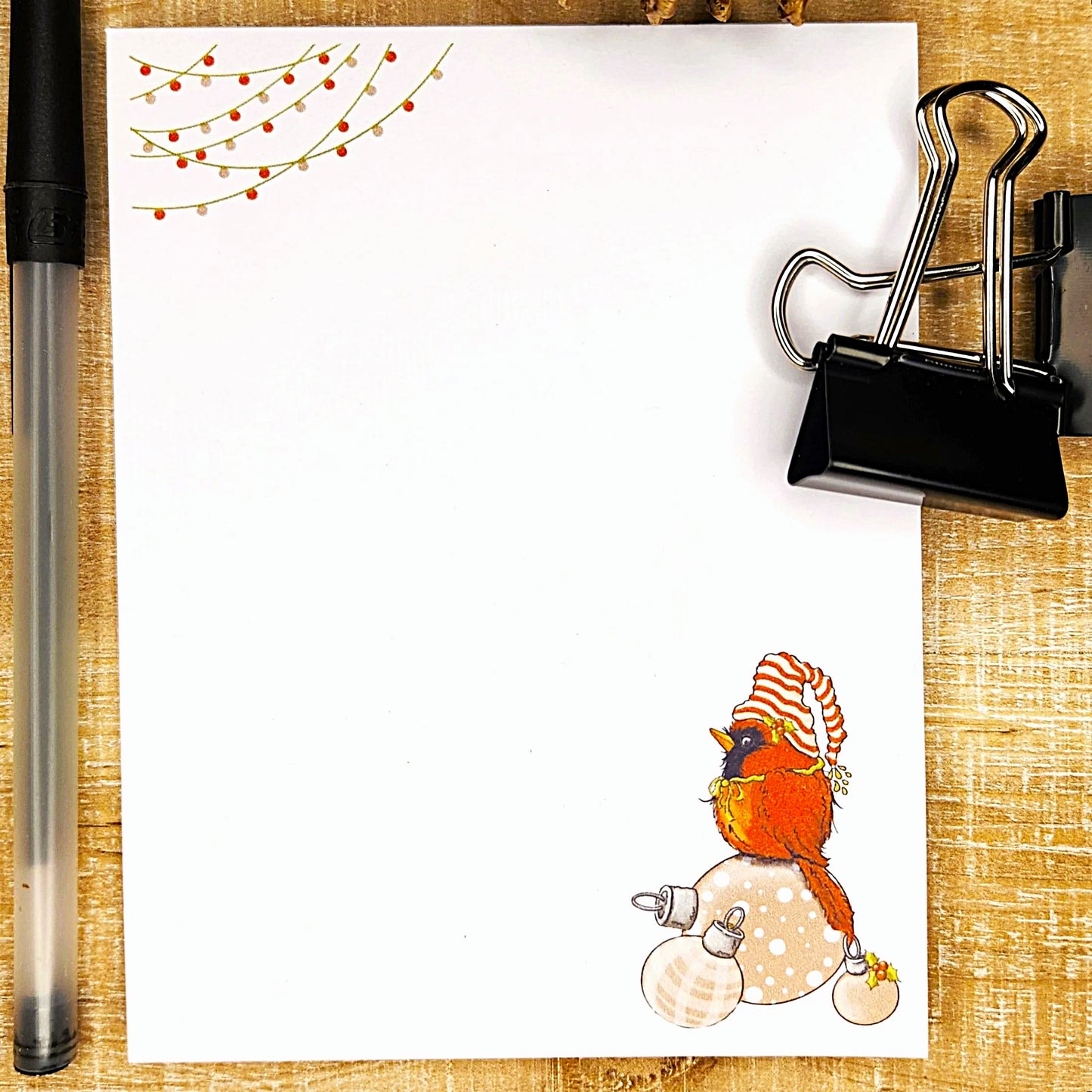Illustration of a cardinal bird on a white card with decorative elements on a wooden surface.