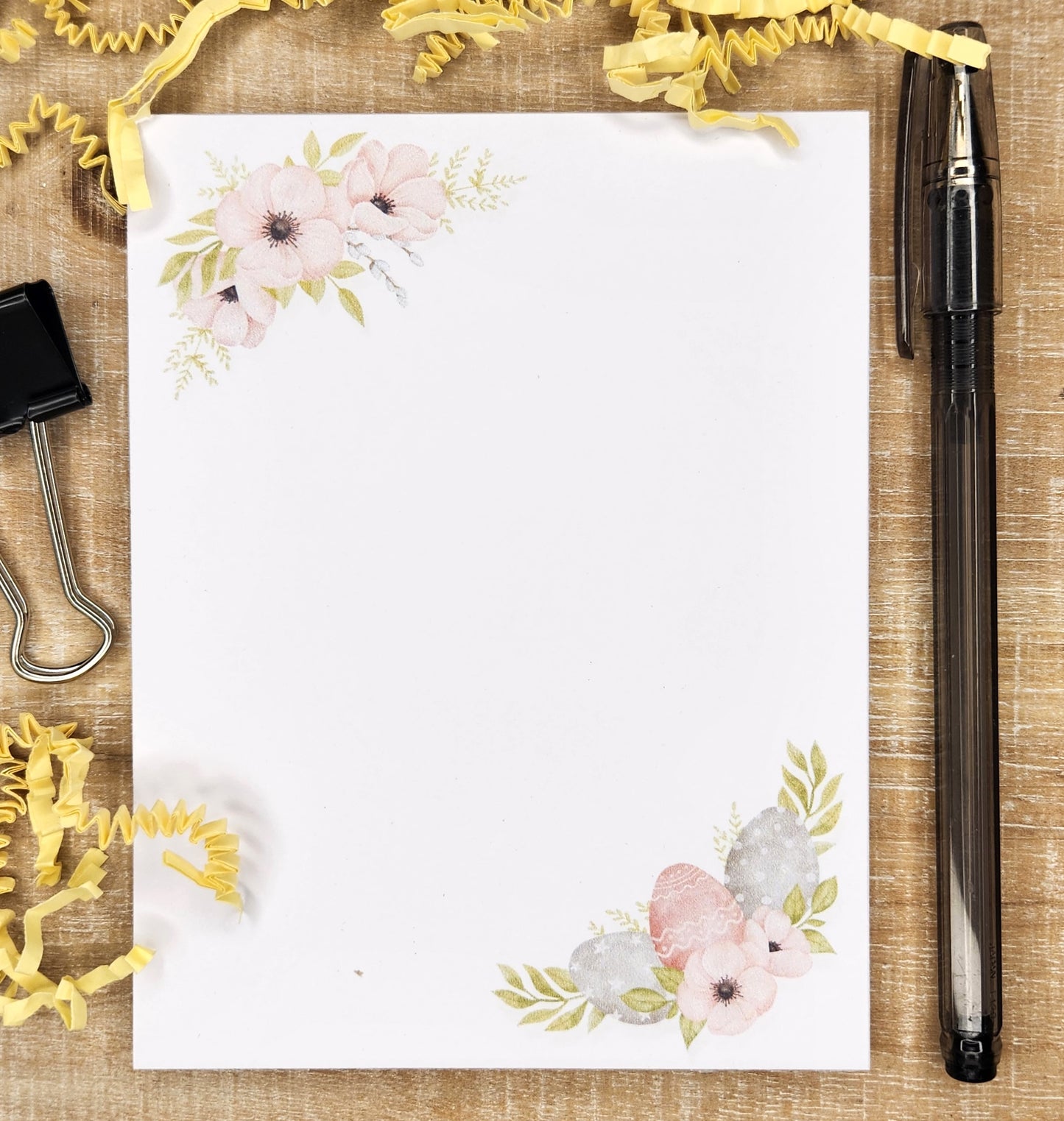 notepad with Easter eggs and florals on the bottom right hand corner and floral spray on the top left hand corner.