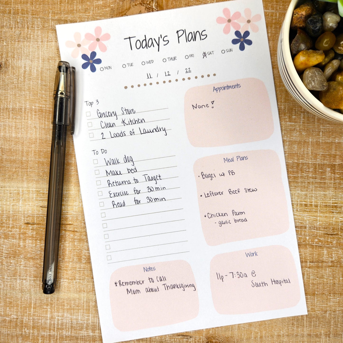 Today's plans planner pad on desk with pen beside it.  Show categories filled out.  Top 3, To Do, Appointments, Meal Plans, Work, Notes.