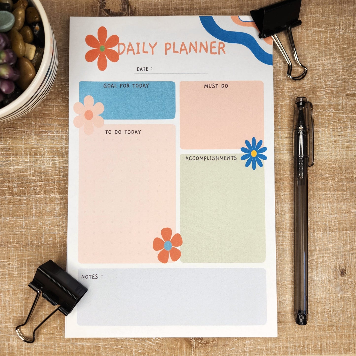 Daily Planner with waves of colors on upper right hand corner.  various flowers accent the page that is filled with different colors of boxes with the headings: date, goal for today, must do, to do today, accomplishments, and notes.
