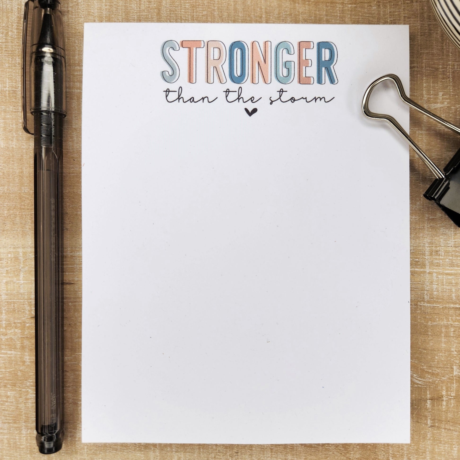 Stronger than the storm is written in block letters in various colors.  Remainder of the notepad is blank.