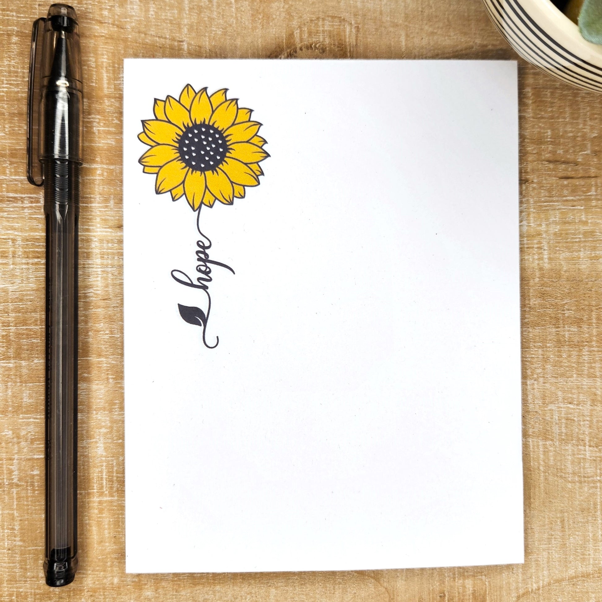white notepad with a sunflower and a word trailing as the stem. Word is  hope