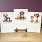 Calendar with illustrations of dogs and cats for October, November, and December on a wooden surface.