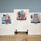 Three calendar pages showing April, May, and June with illustrated houses and flowers on a wooden surface.