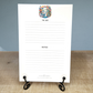 White notepad with decorative bicycle design and text on a wooden surface.