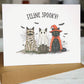 Halloween-themed card with cats dressed in costumes on a white background