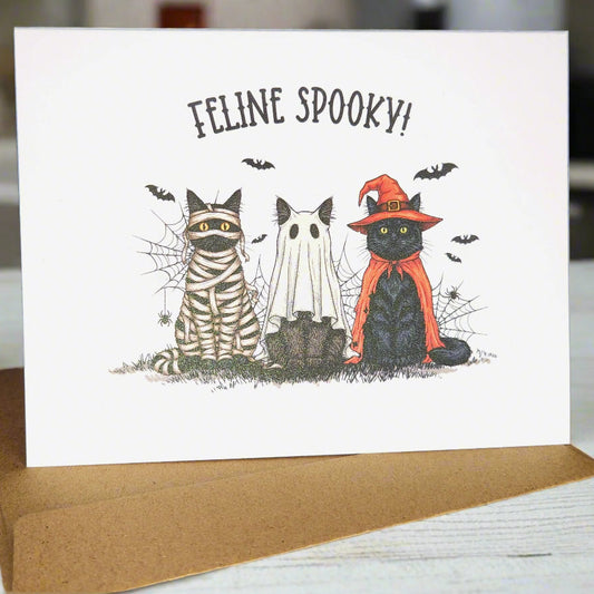 Halloween-themed card with cats dressed in costumes on a white background