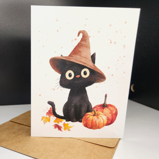 black kitten in tan hat with pumpkin and leaves surrounding it.  All this cuteness on a greeting card