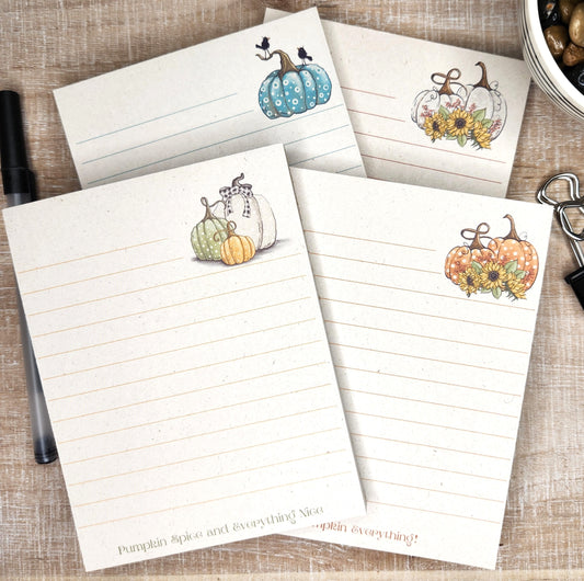 4 beige sugarcane notepads on a black background. Each notepad depicts a different pumpkin with saying on the bottom of the page.