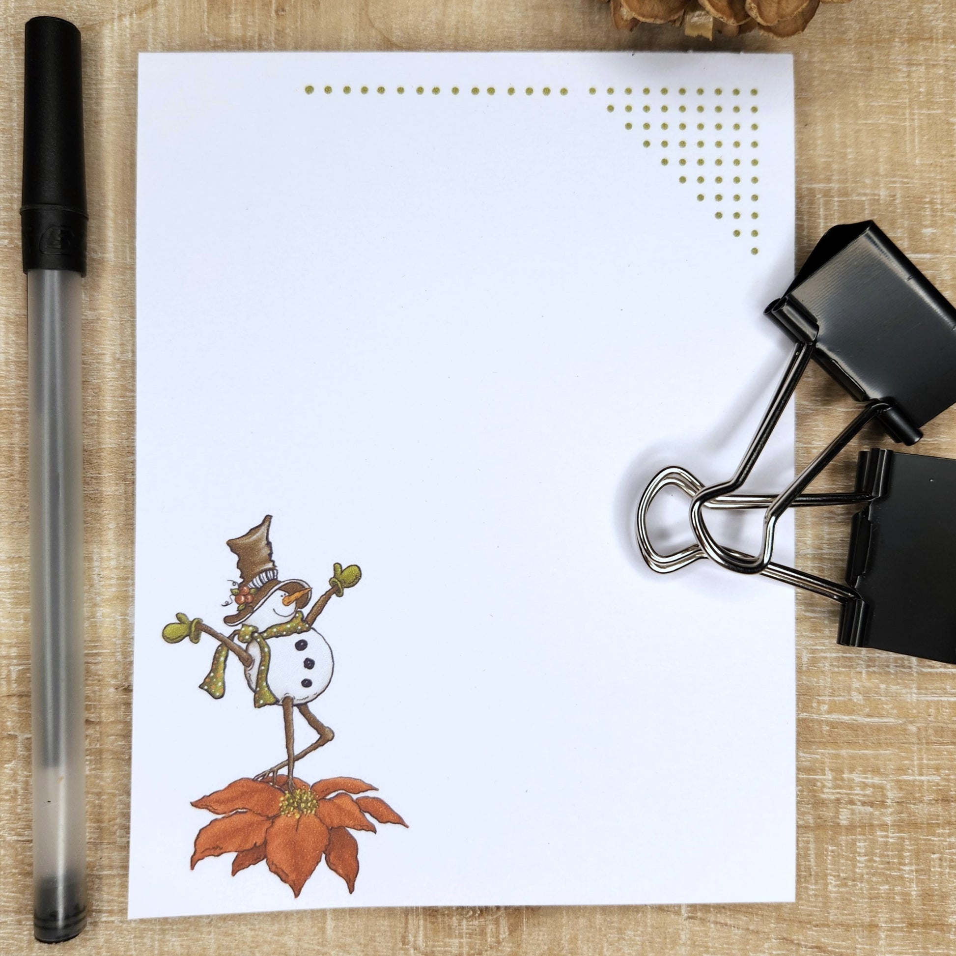 white notepad on tan and red background. Green dots accent the top of the page. snowman dancing on a poinsettia on the bottom left corner of the page.