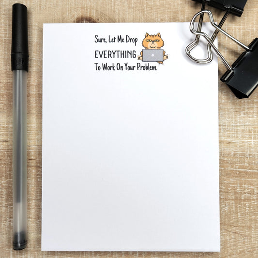 notepad with a cat with a grumpy face.  words on notepad reads "Sure, let me drop everything to work on your problem.