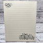 Soft beige sugarcane paper notepad on white barn board background.  Note pad is lined and has ladybug accent on the upper left and flowers on the bottom right corner.  all designs are line drawings. 