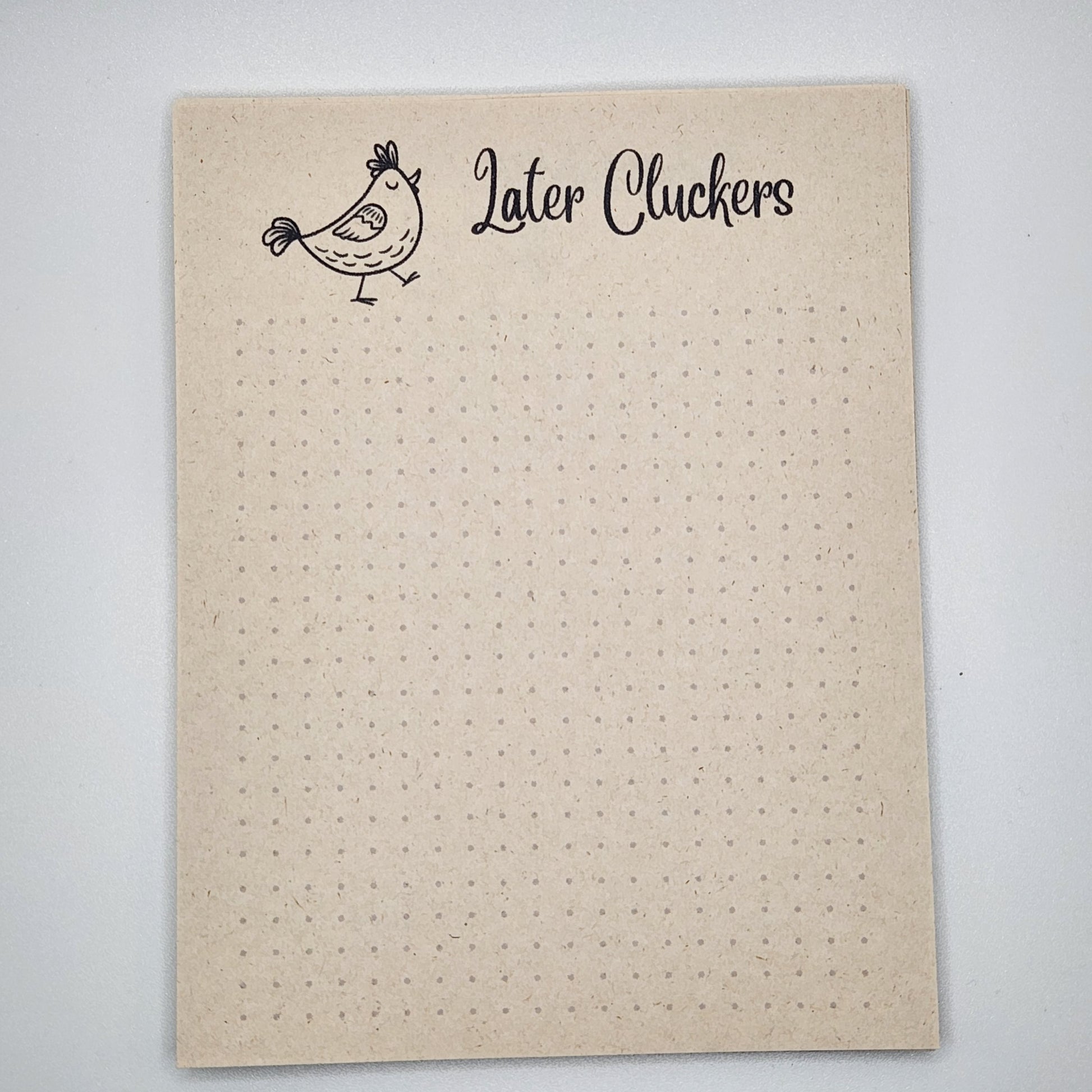 Natural sugarcane notepad on white background. Cartoon chicken at the top is walking toward the right.  the words Later Cluckers is written to the right of the chick.  The remainder of the notepad is filled with light dots.