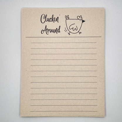 Natural sugarcane notepad on white background. Cartoon chicken at the top is running to the left and the words Cluckin' Around is written to the left of the chick.  Lines fill the remainder of the page. 