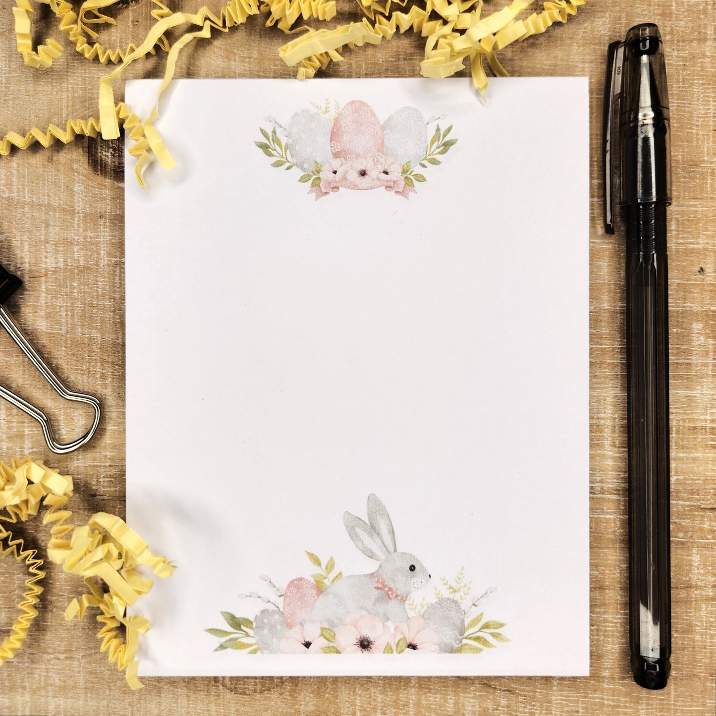 Notepad with gray bunny in a spray of eggs and flowers.  Top of the notepad show three eggs in florals. 