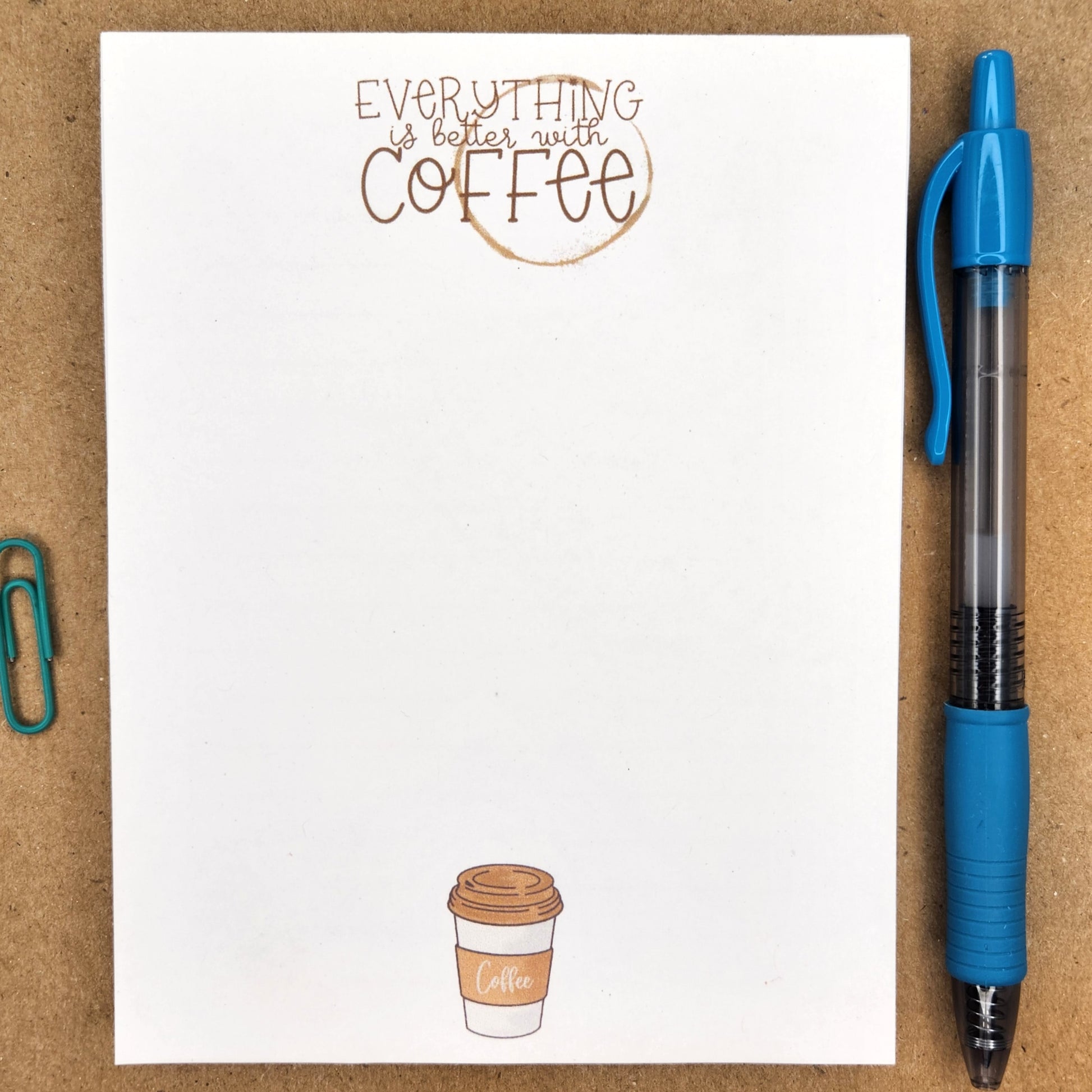 notepad is sitting on a tan background.  the top center of the notepad has a coffee ring and the words 'everything is better with coffee' over the ring.  the bottom center of the notepad has the image of a to go cup of coffee. 