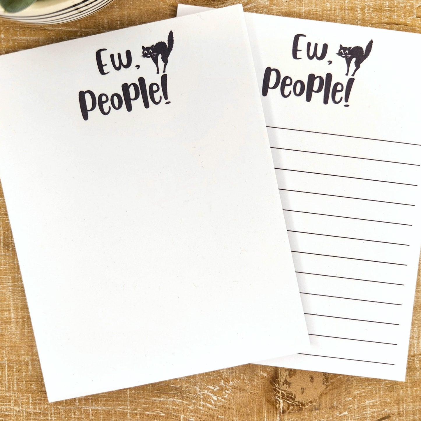 Picture of both notepad designs, one unlined, one lined. The saying is Ew, People! with a scared looking black cat