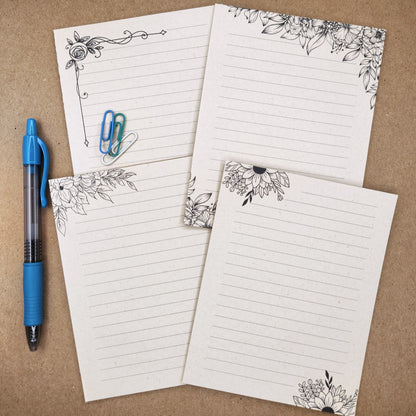 4 Sugarcane paper notepads are arranged on a tan background. Each notepad set is accented by black line drawings of flowers.