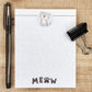 White notepad on a tan background. Kitten with mouth open graces the top center of the page. Black line accents the top as well. Faint cat faces are throughout the page and the word MEOW in on the center bottom of the page.