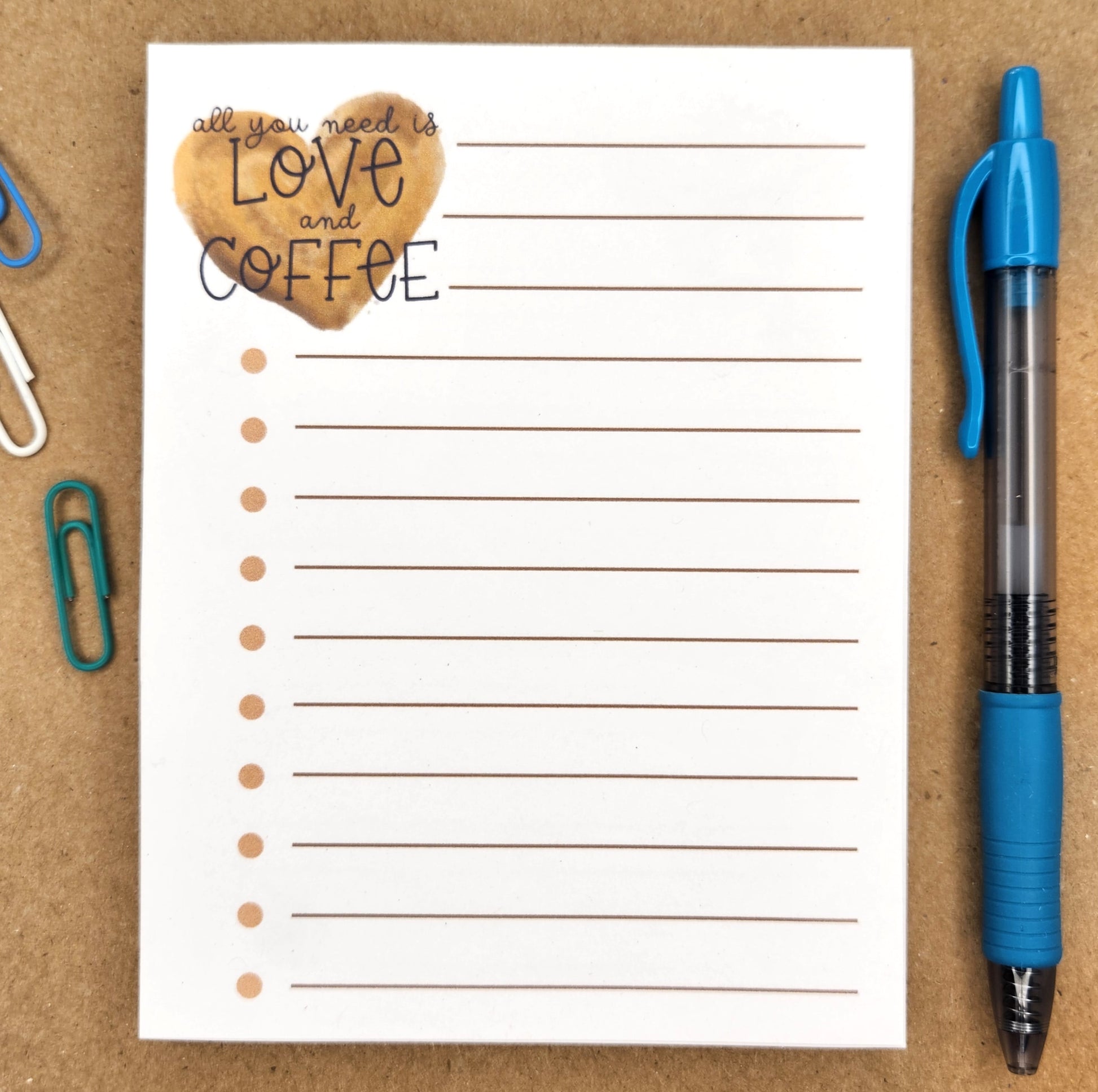 notepad is lined with dots at the beginning of each line.  the upper left corner of the page is a coffee colored heart with the words 'all you need is love and coffee' over the heart.