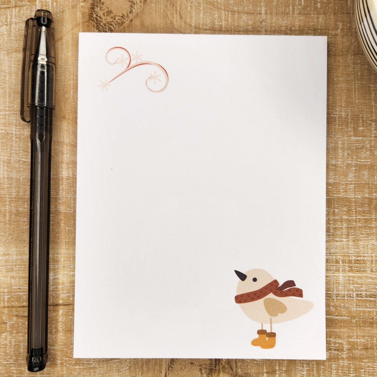 notepad with small bird wearing a scarf and boots are on the bottom right corner.  a gust of wind with snow flakes is in the upper left corner.