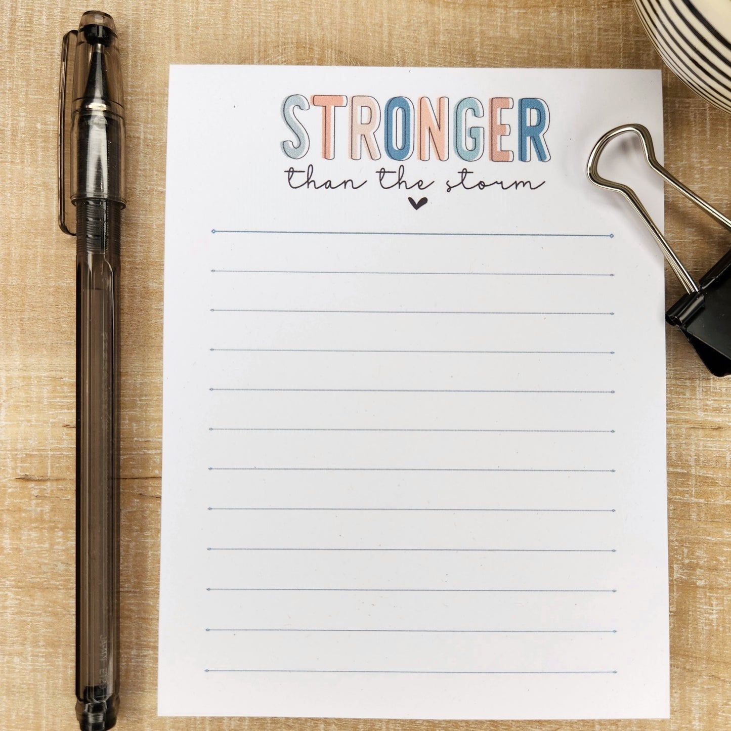 Stronger than the storm is written in block letters in various colors. Remainder of the notepad has lines