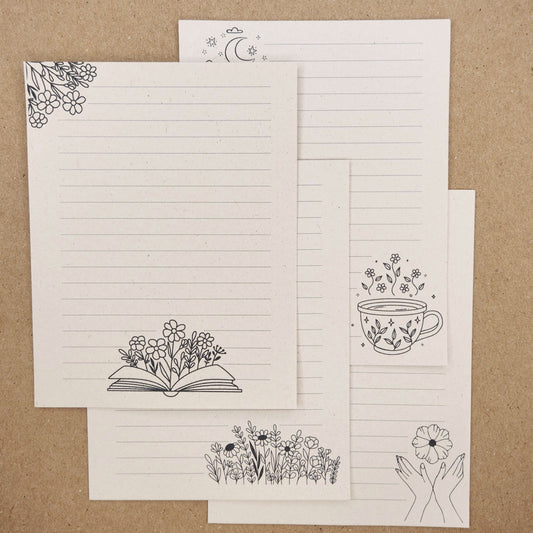 4 beige sugarcane paper notepads on tan background. each notepad is lined with various line drawing accents.